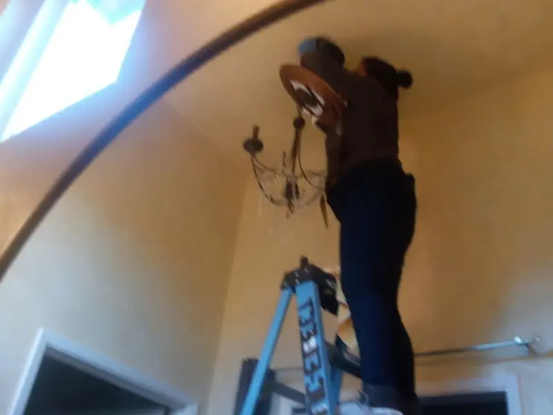 Electrician installing a chandelier in a Plover residence